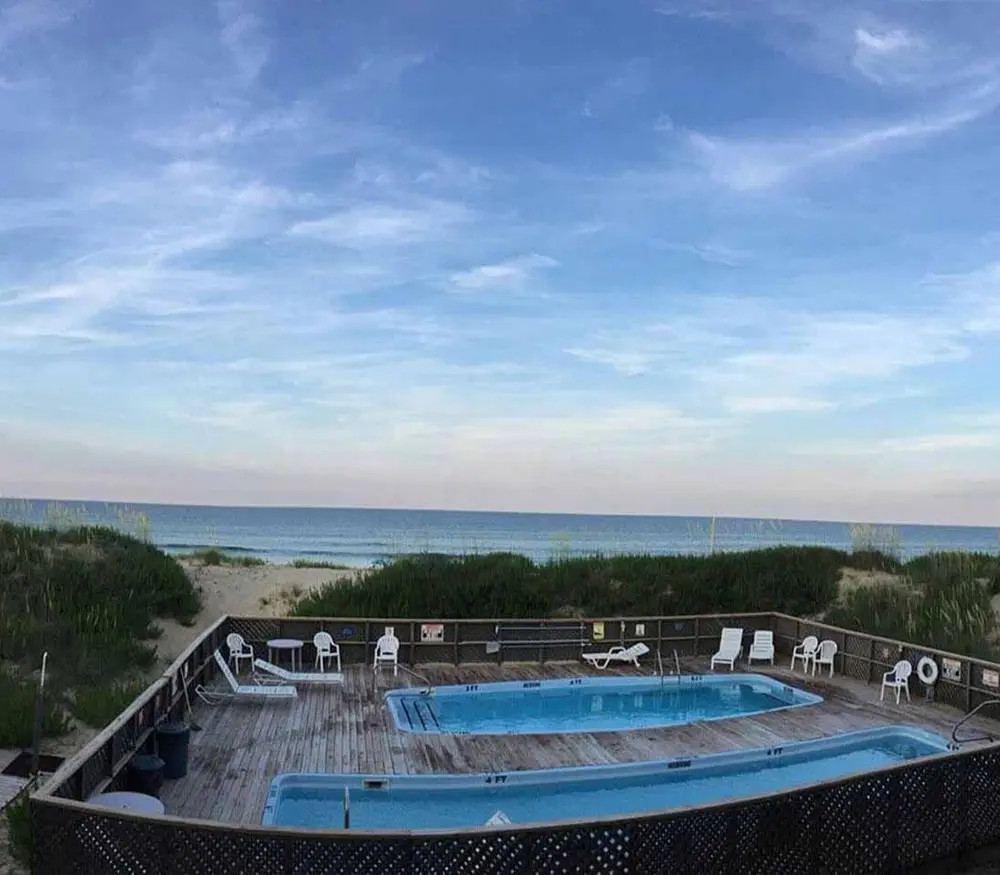 The Blue Heron Motel pool deck, with white loungers around an outdoor pool and the Atlantic beyond the rail