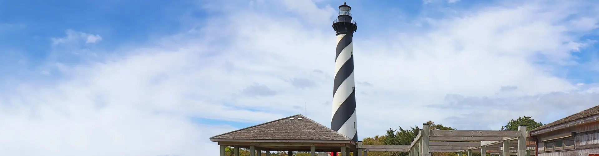 Cape Hatteras Lighthouse, its black spiral stripes rising above the rooftops into a bright blue sky
