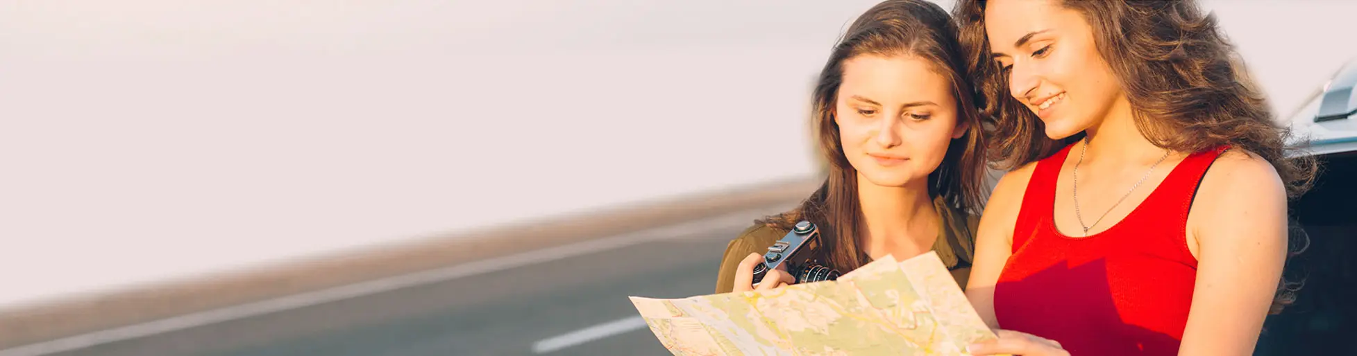 Two young women in a car poring over an unfolded paper road map
