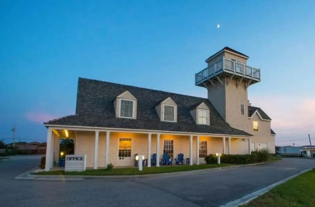 Hatteras Island Inn at dusk, its lit porch running the length of the building beneath the observatory tower