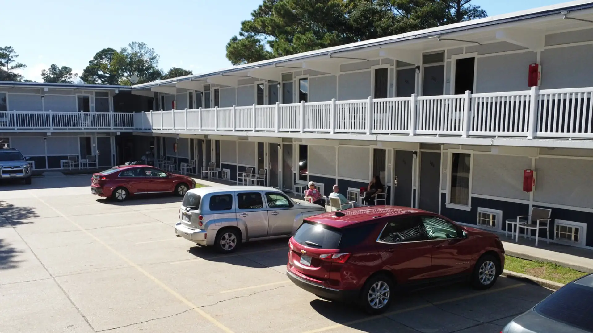 The Heart of Manteo Motor Lodge, a two-storey white building with a balcony walkway above the car park