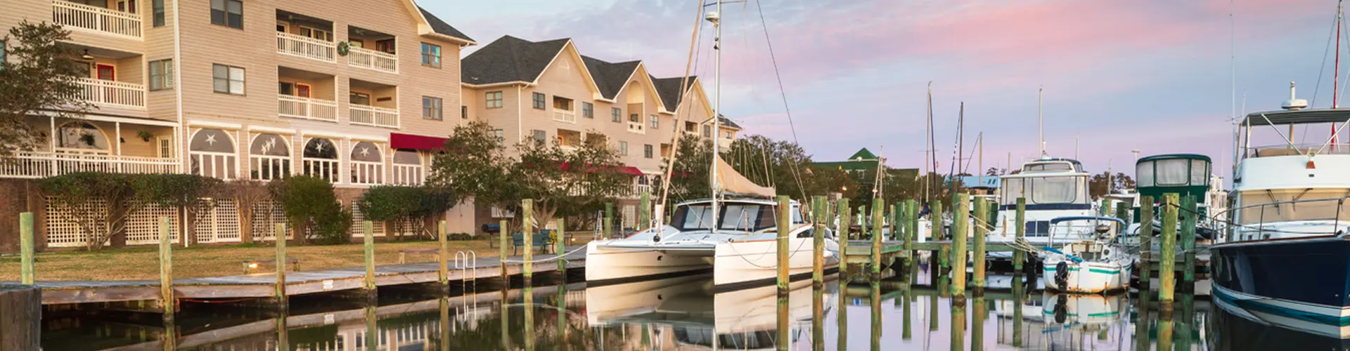 Pleasure boats tied up beneath waterfront condominiums, their reflections still on the harbour water