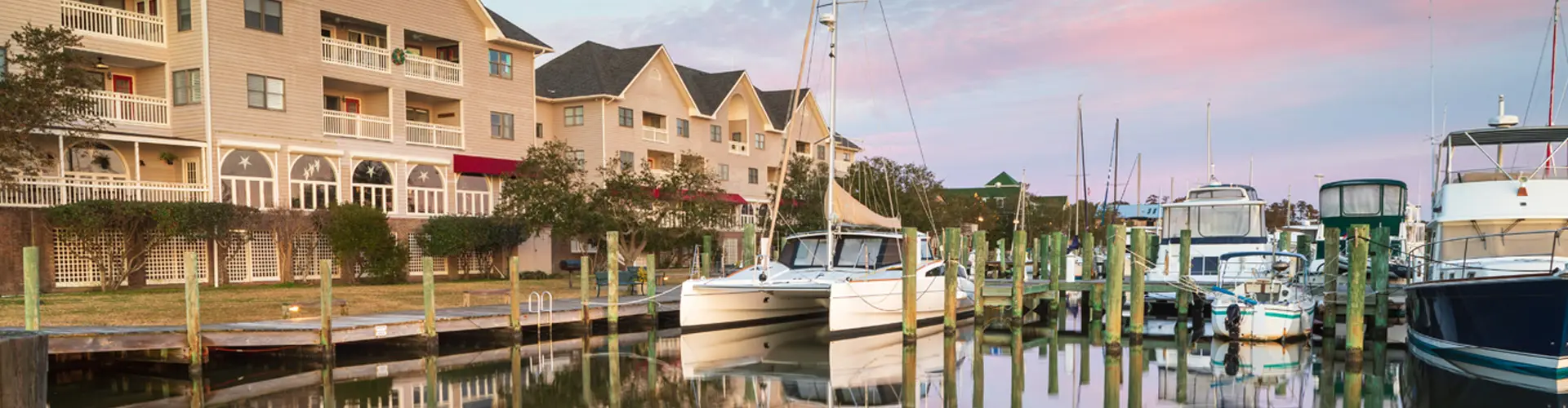 Pleasure boats tied up beneath waterfront condominiums, their reflections still on the harbour water