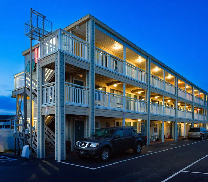 The Seahorse Inn & Cottages lit at night, three storeys of balconies above the car park