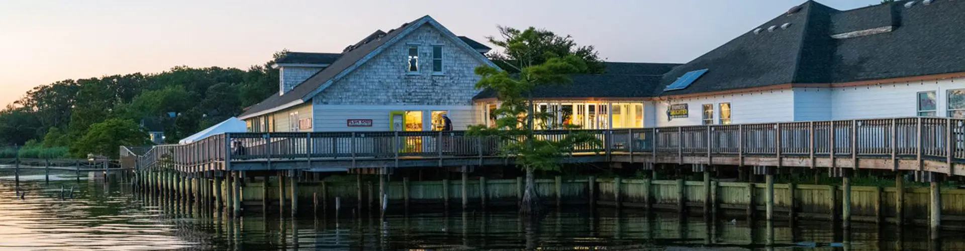 Soundfront shops and a restaurant on pilings, joined by a wooden boardwalk over the water