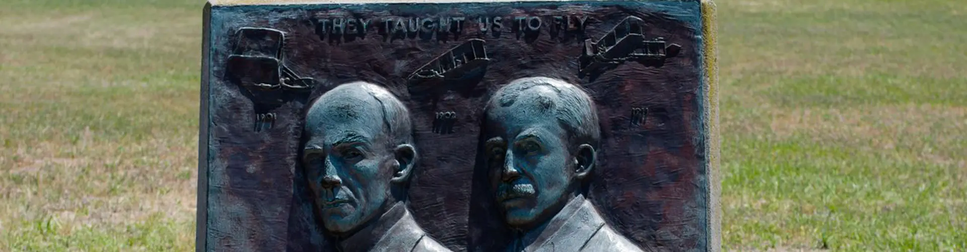 A bronze relief plaque of the two Wright brothers set in a stone marker on open grass