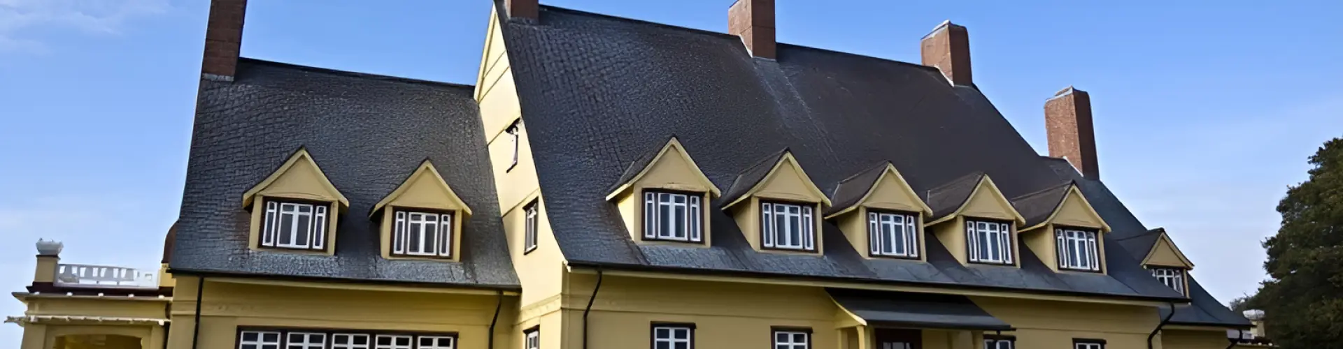 The Whalehead house in Corolla, its yellow walls and steep grey gambrel roof set among trees